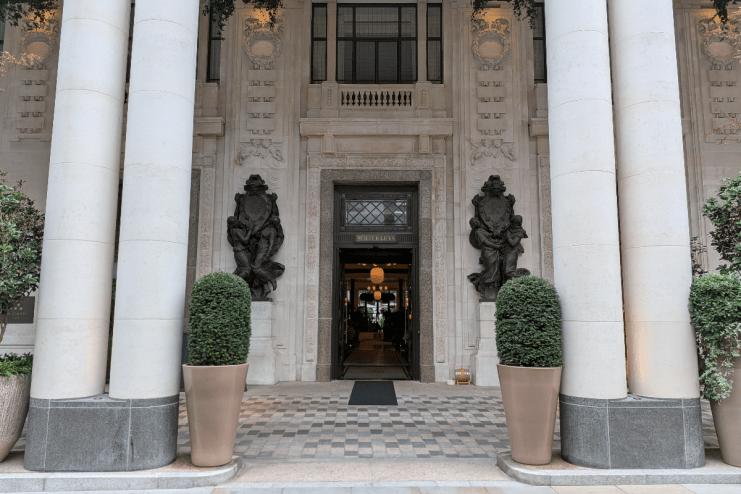 Grand entrance of Six Senses London, featuring large pillars, ornate sculptures, and a WHITELEYS sign above the door.