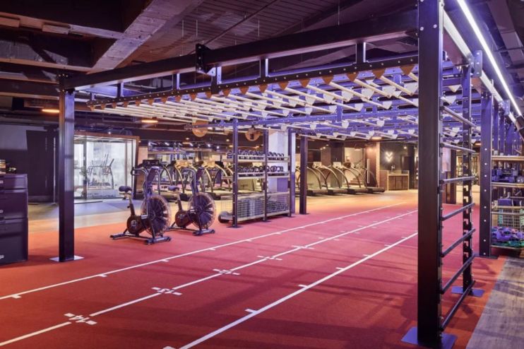 Modern gym interior with red track, workout equipment, treadmills, and monkey bars, representing a Third Space fitness fac...