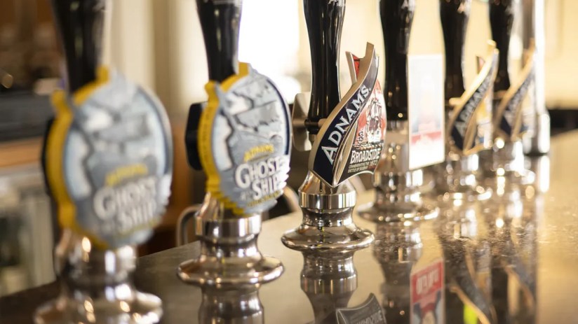 Adnams beer pumps lined up on a bar, with Broadside and Ghost Ship visible on the handles.