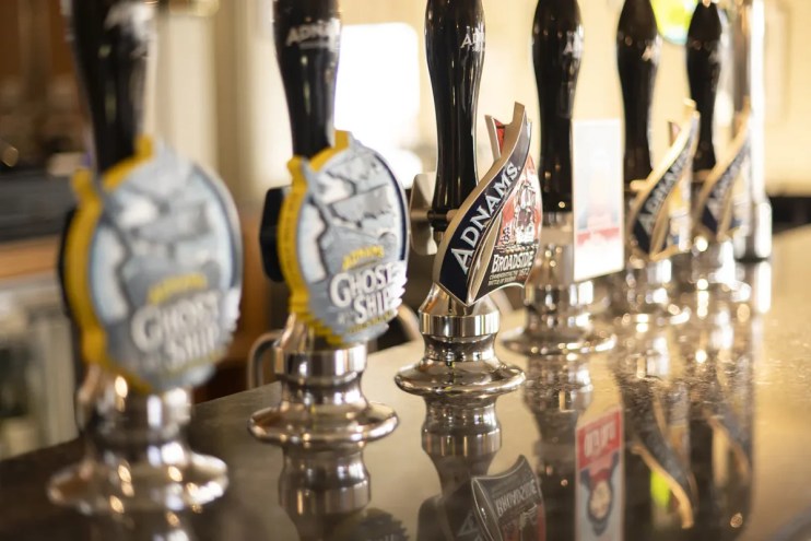 Adnams beer pumps lined up on a bar, with Broadside and Ghost Ship visible on the handles.