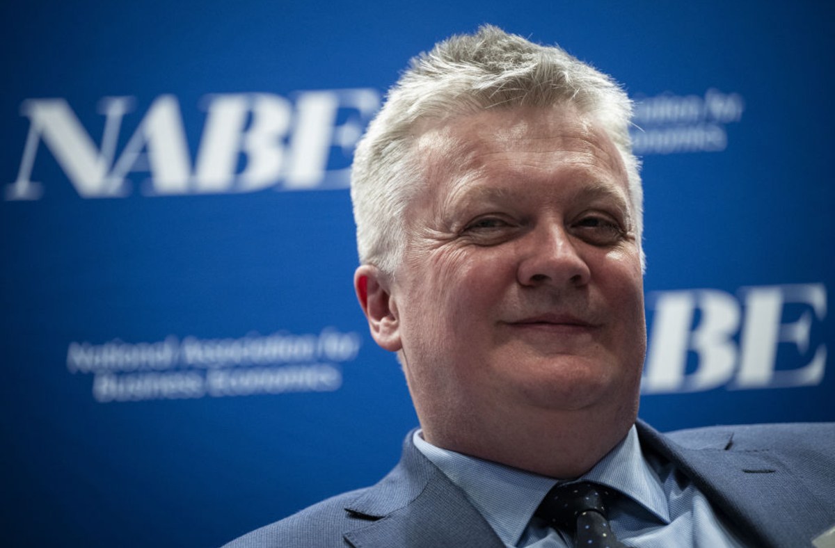 Huw Pill, Bank of England Chief Economist, smiling in a suit and tie against a blue NABE banner.