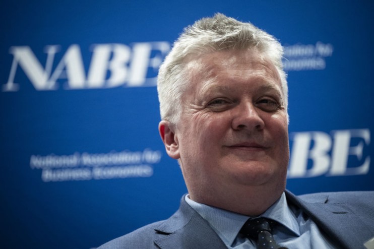 Huw Pill, Bank of England Chief Economist, smiling in a suit and tie against a blue NABE banner.