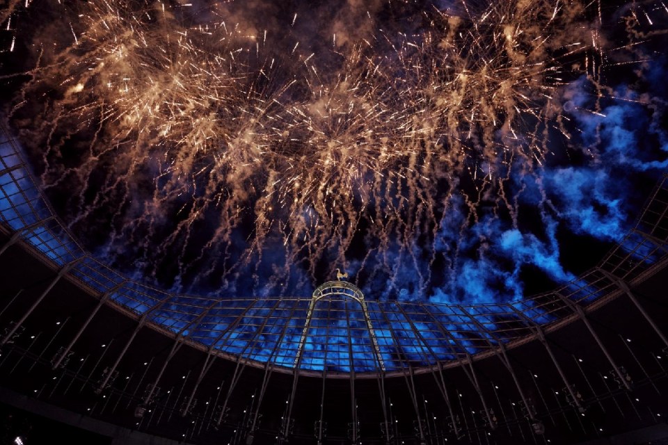 Fireworks exploding over Tottenham Hotspur Stadium at night, with the stadium roof and cockerel visible
