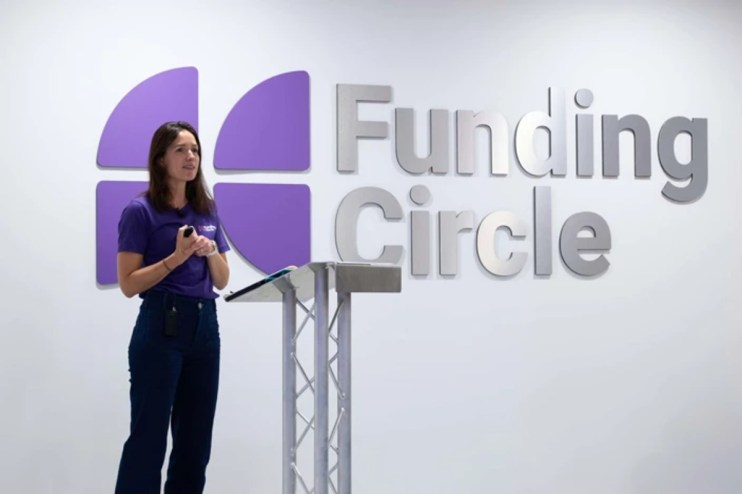 Woman in purple shirt speaking at a podium with Funding Circle logo on the wall