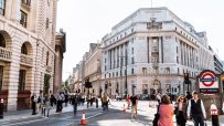 Busy street scene in London with historic buildings, pedestrians, traffic, and a Bank Underground station sign.
