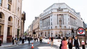Busy street scene in London with historic buildings, pedestrians, traffic, and a Bank Underground station sign.