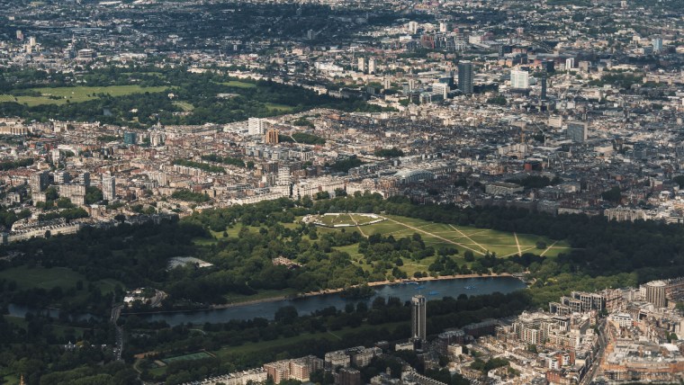 Aerial view of London cityscape with Hyde Park, Serpentine Lake, and surrounding urban buildings