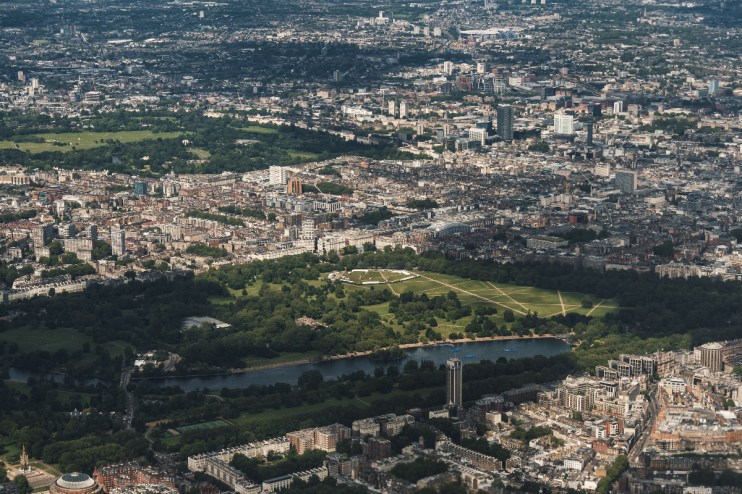 Aerial view of London cityscape with Hyde Park, Serpentine Lake, and surrounding urban buildings
